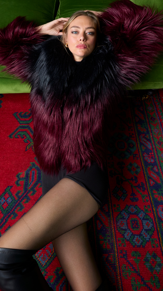 Woman wearing a fur coat lying on a colorful rug